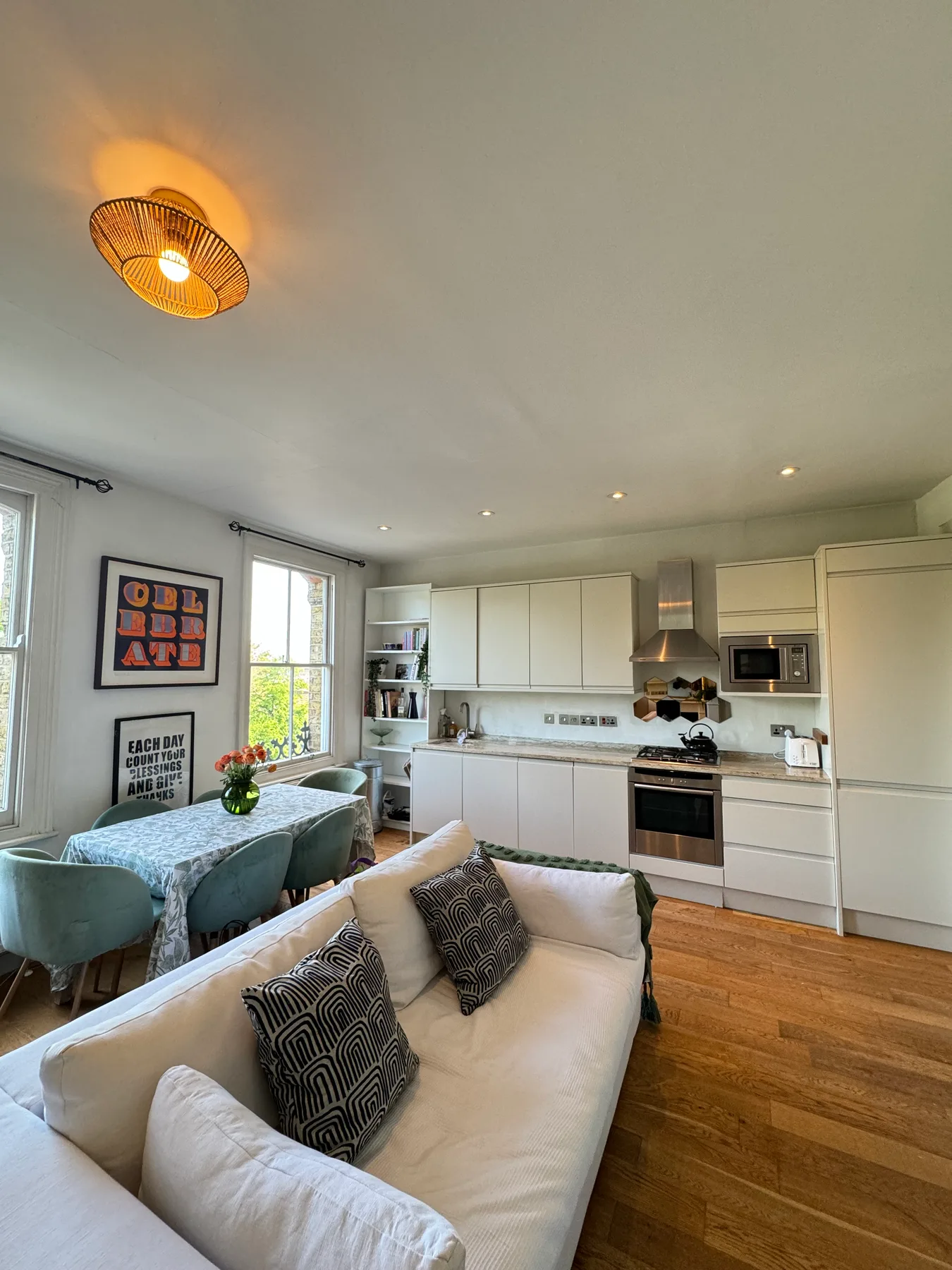 A bright open-plan living room and kitchen with a sofa and dining table.