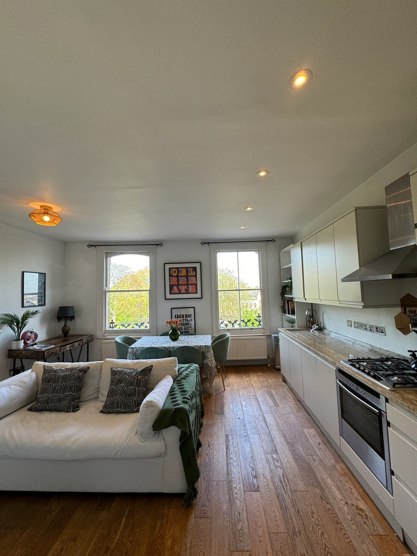 A bright open-plan living room and kitchen with windows along the back wall.