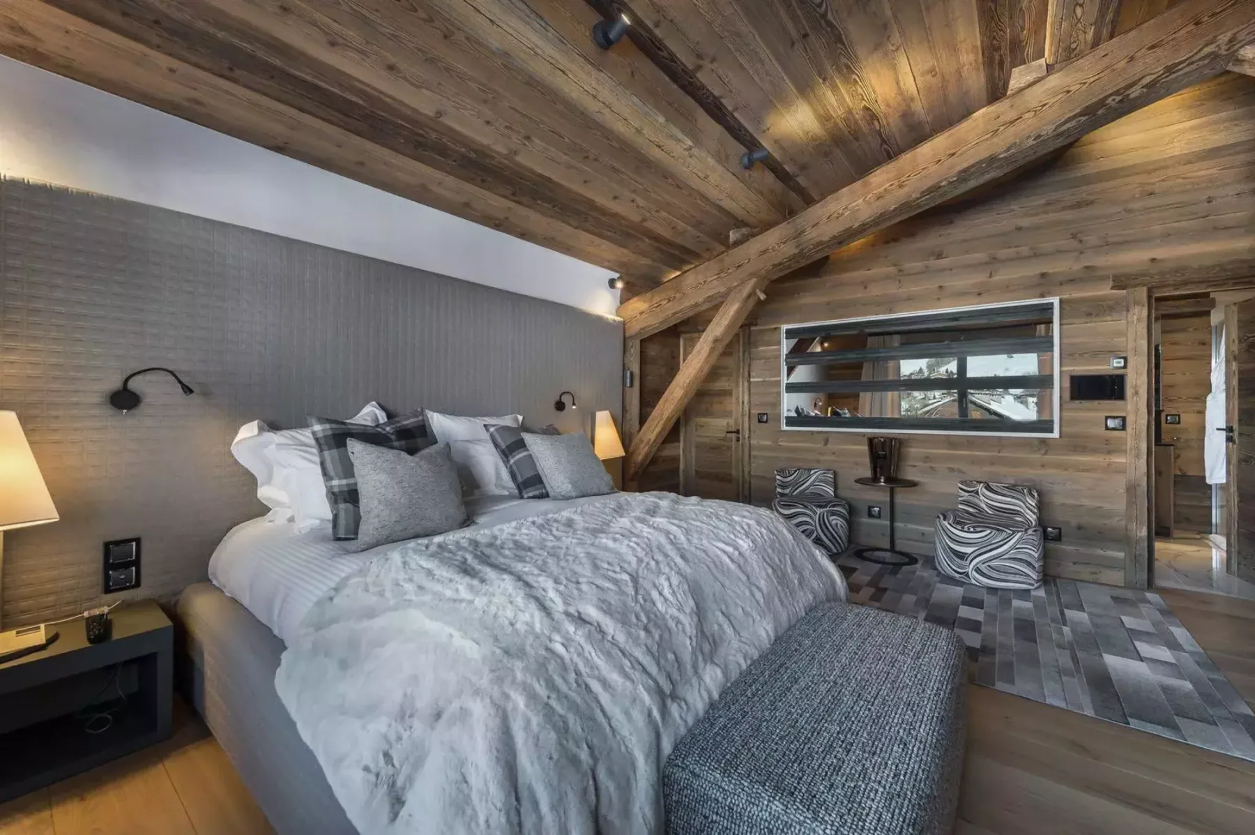A bedroom with a large bed beneath a sloped wooden ceiling.