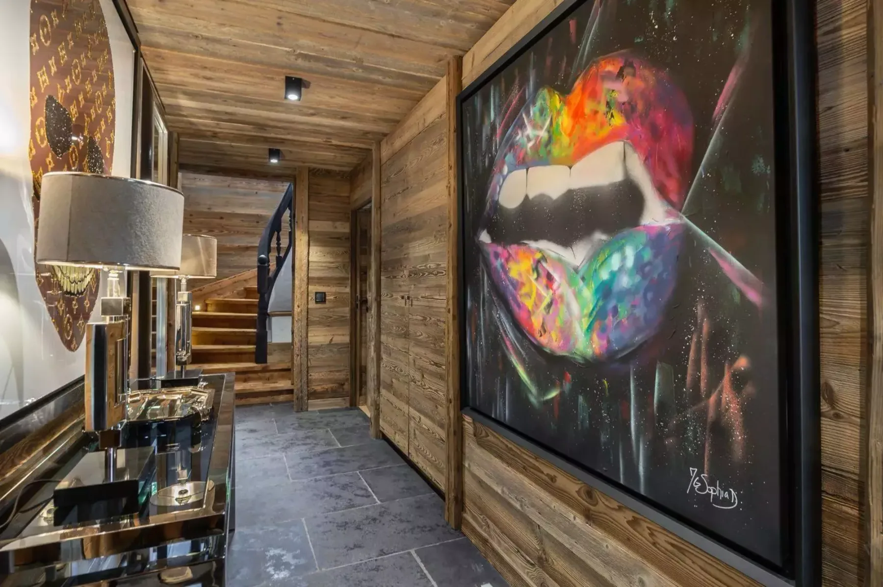 A wood-paneled hallway features colorful artwork and stairs at the far end.