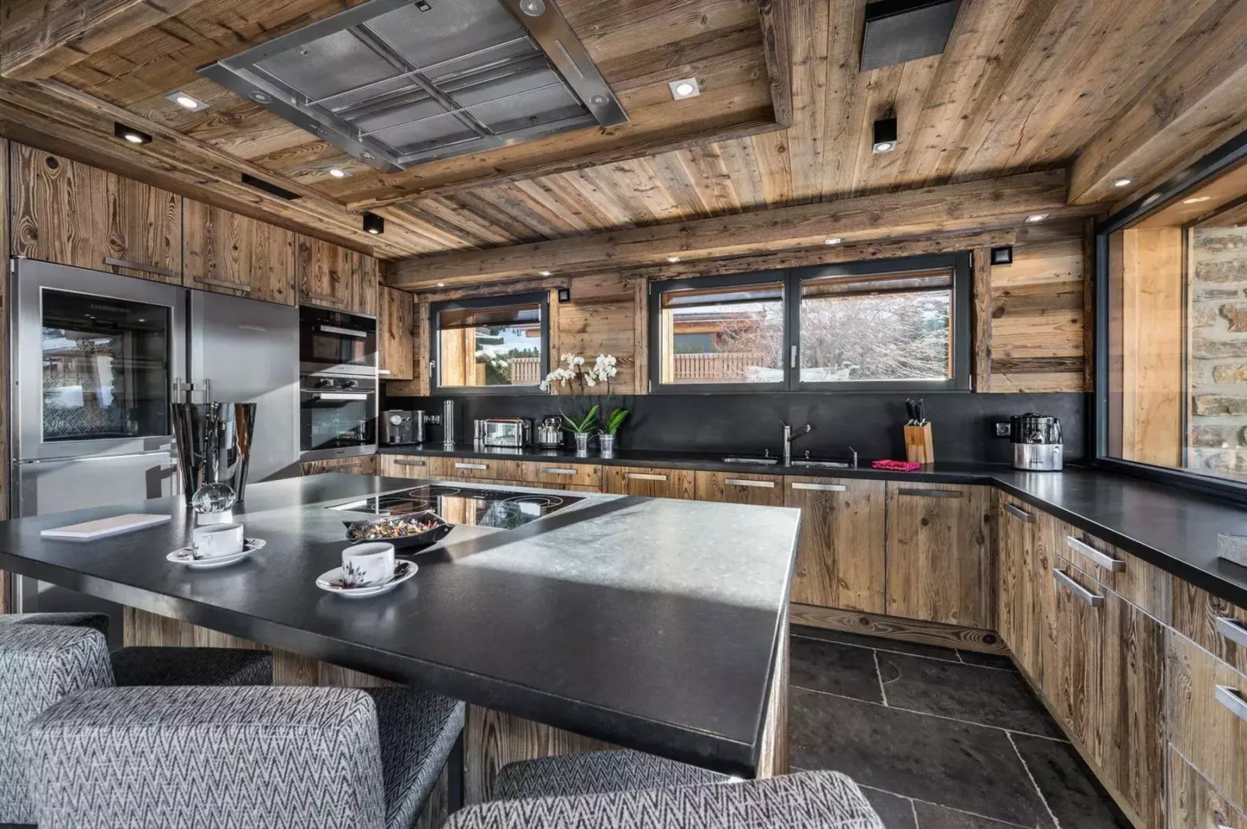 A wood-paneled kitchen with dark countertops, built-in appliances, and a central island.