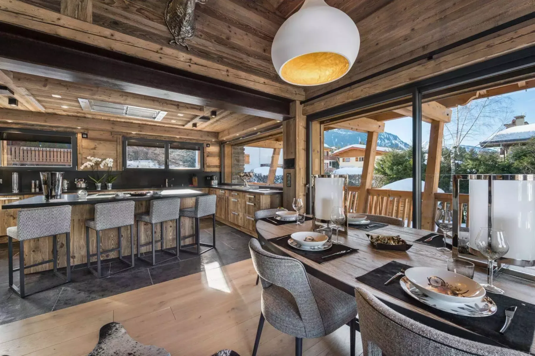 A wood-paneled dining and kitchen area with a long table and breakfast bar.
