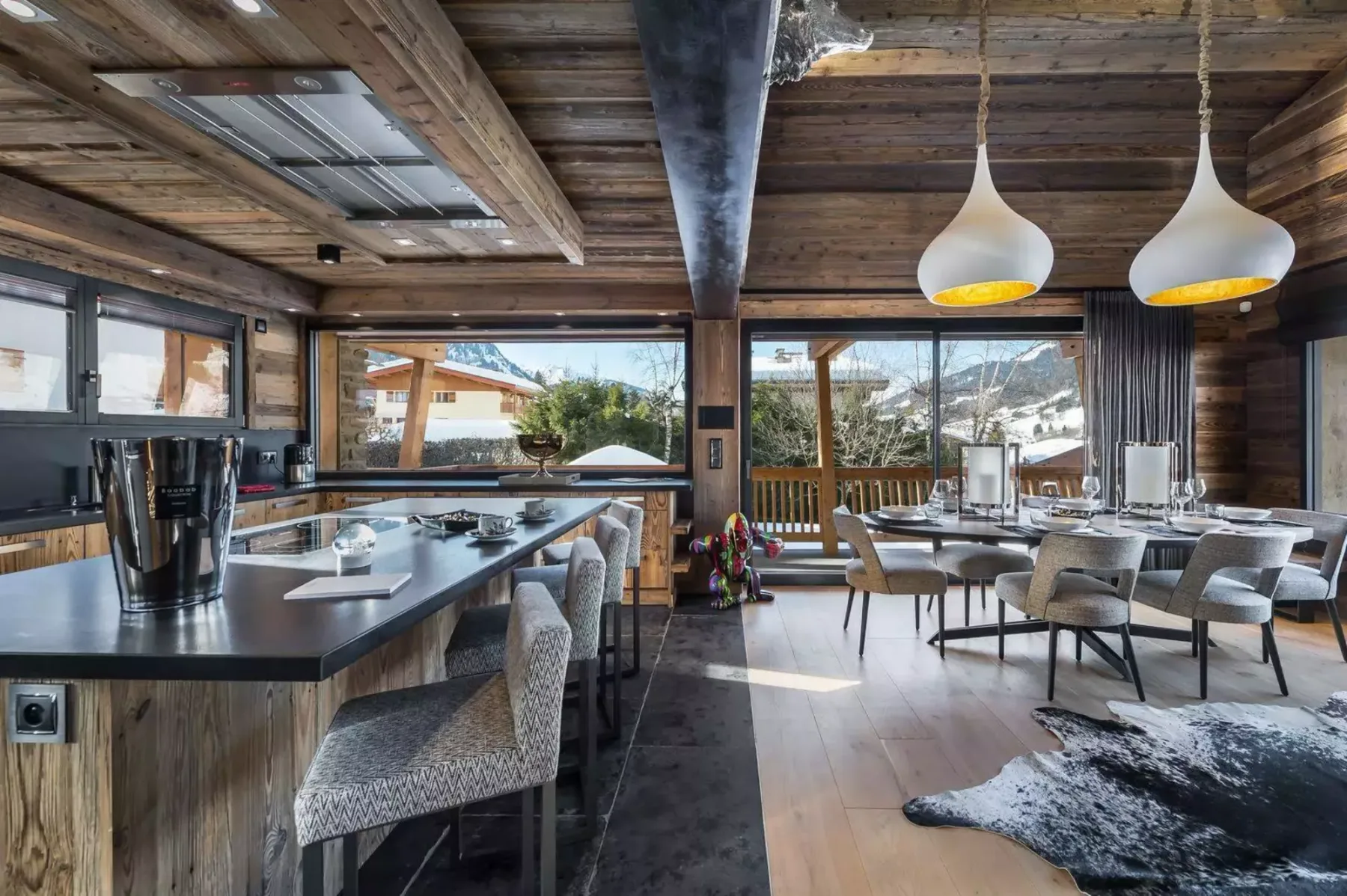 A wood-paneled dining and kitchen area with large windows overlooking a mountain view.