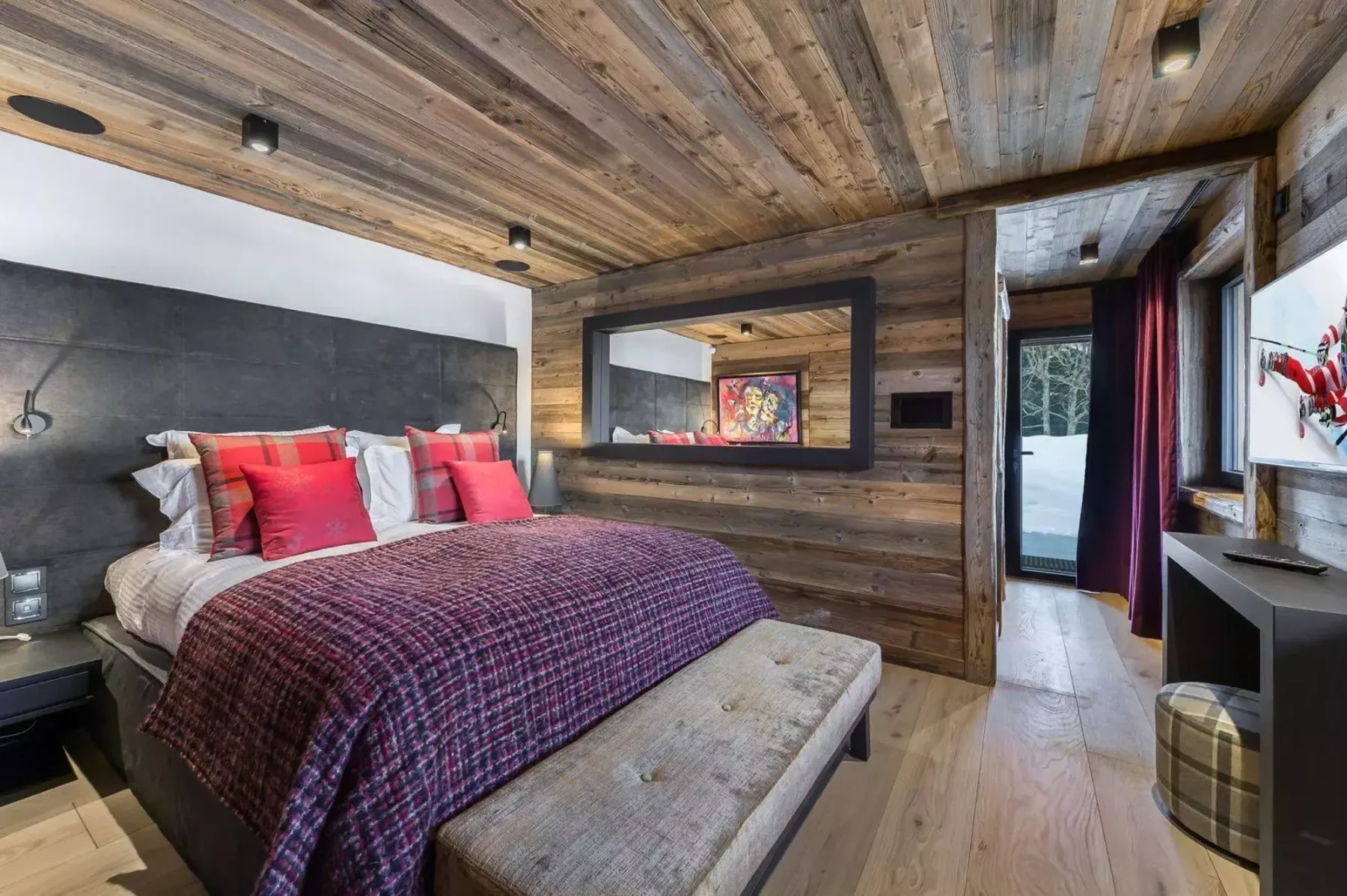 A bedroom with a bed, a cushioned bench, and wood-paneled walls.