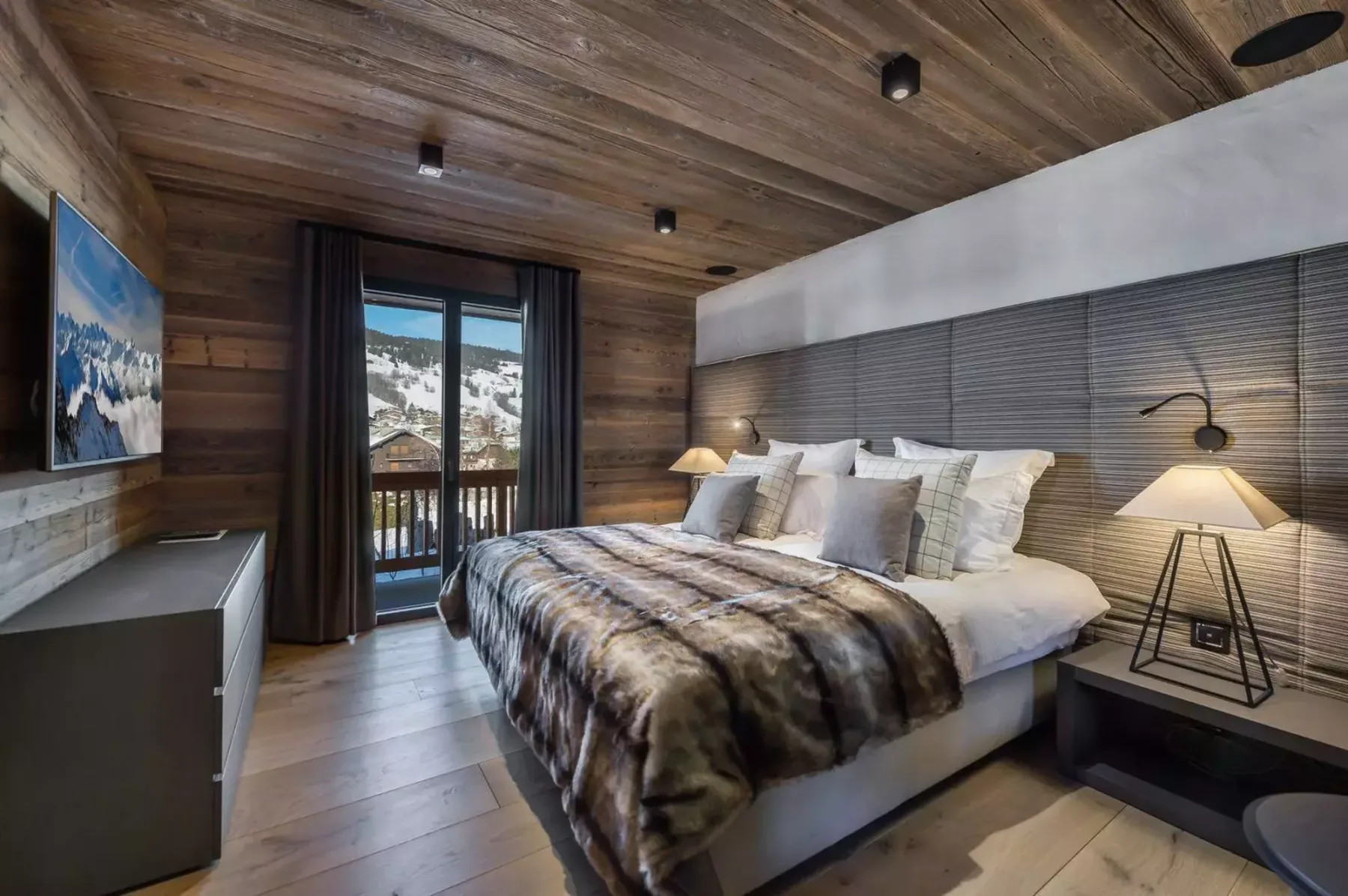 A bedroom with a large bed beside a window overlooking a snowy landscape.