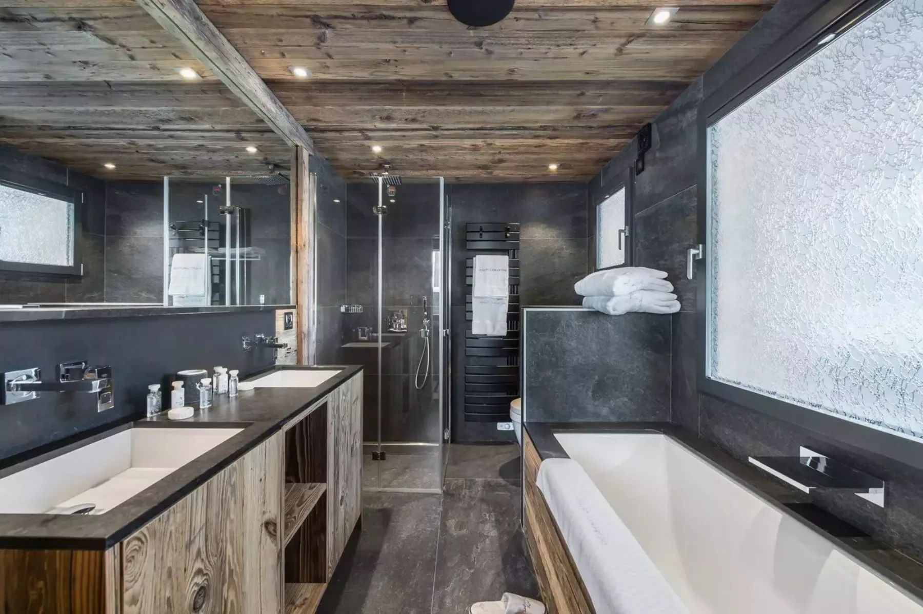 A modern bathroom with a bathtub, vanity, and glass shower.