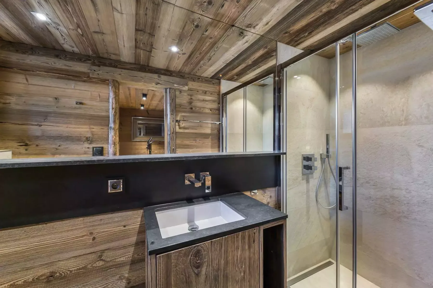 A wood-paneled bathroom has a vanity sink and glass shower.