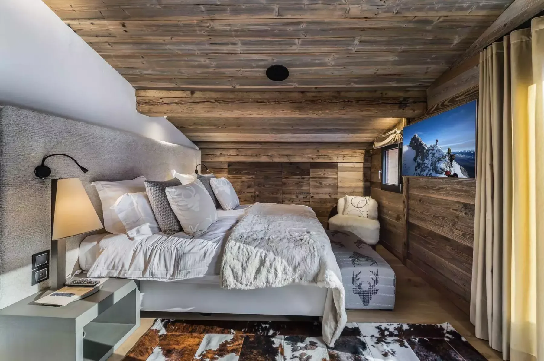 A wood-paneled bedroom with a bed beneath a low timber ceiling.