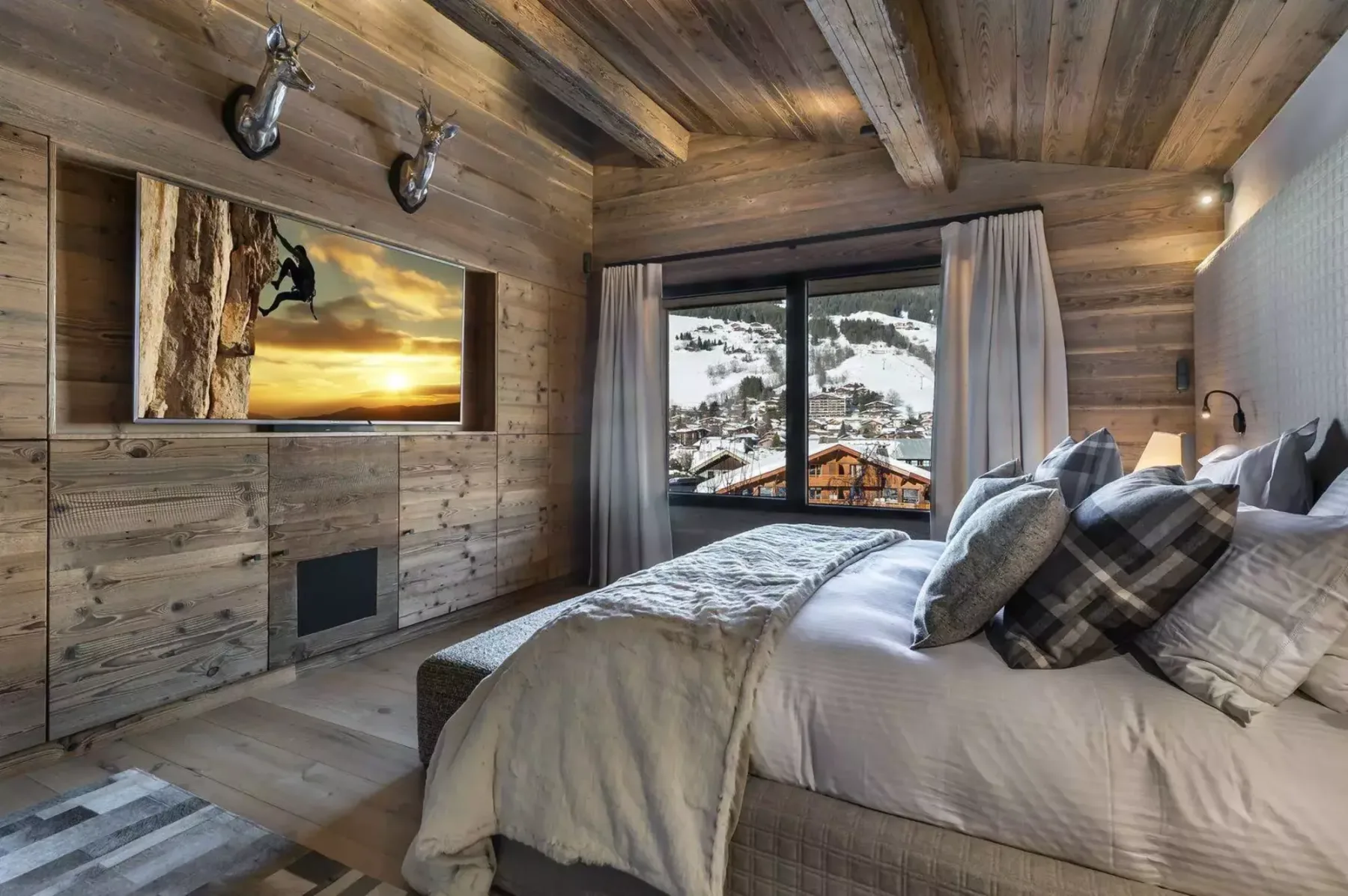 A bedroom with a large bed and a window overlooking snowy mountains.