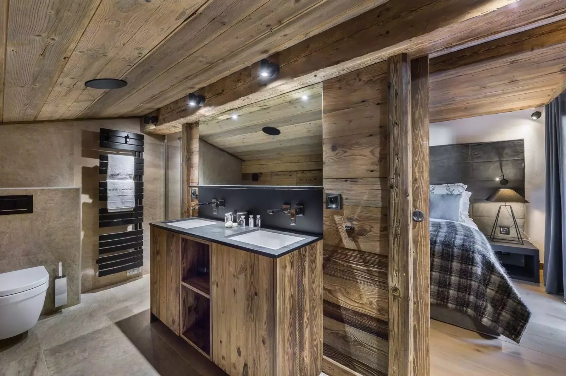 A wood-paneled bedroom and bathroom area with a small kitchenette in the foreground.