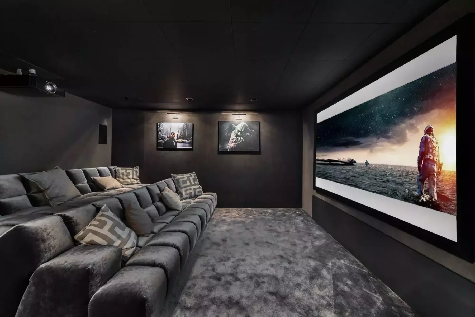 A dark home theater with sectional seating and a large screen.