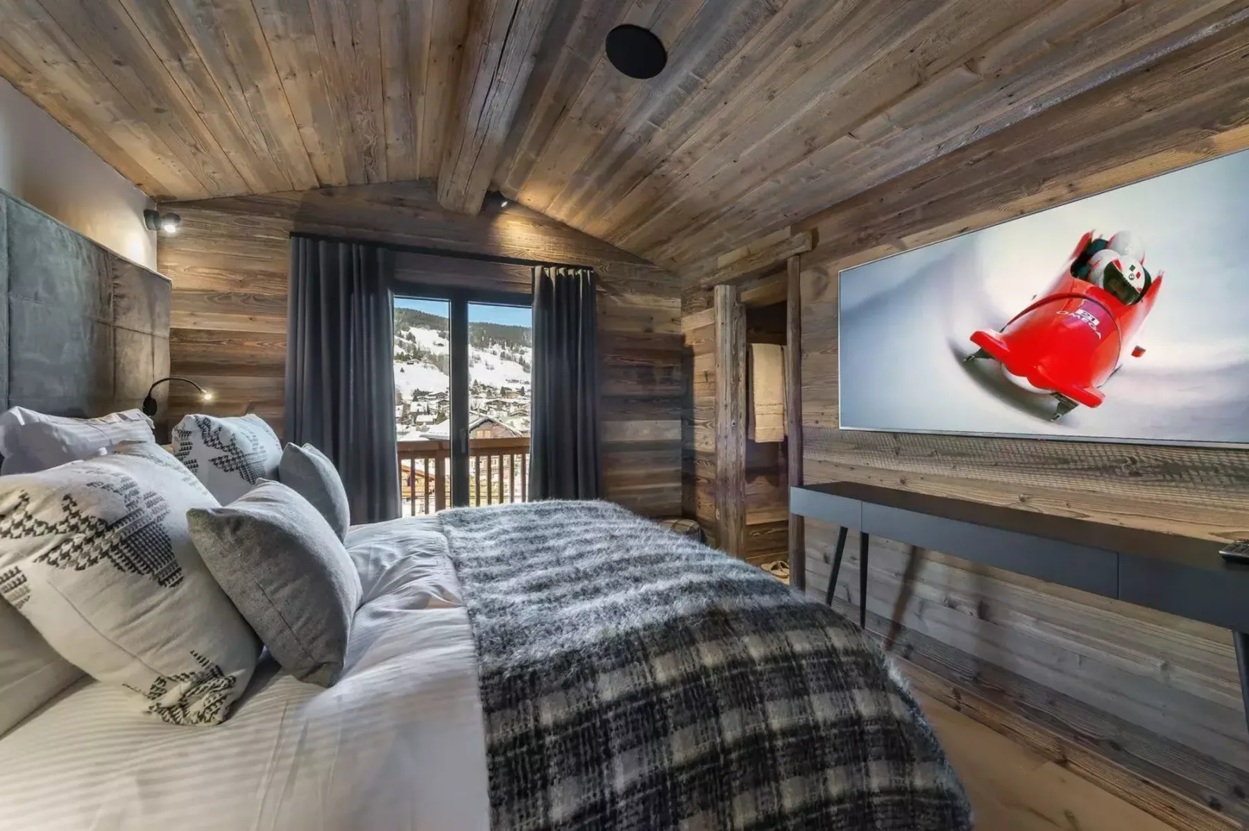 A wood-paneled bedroom with a bed facing a wall-mounted television.