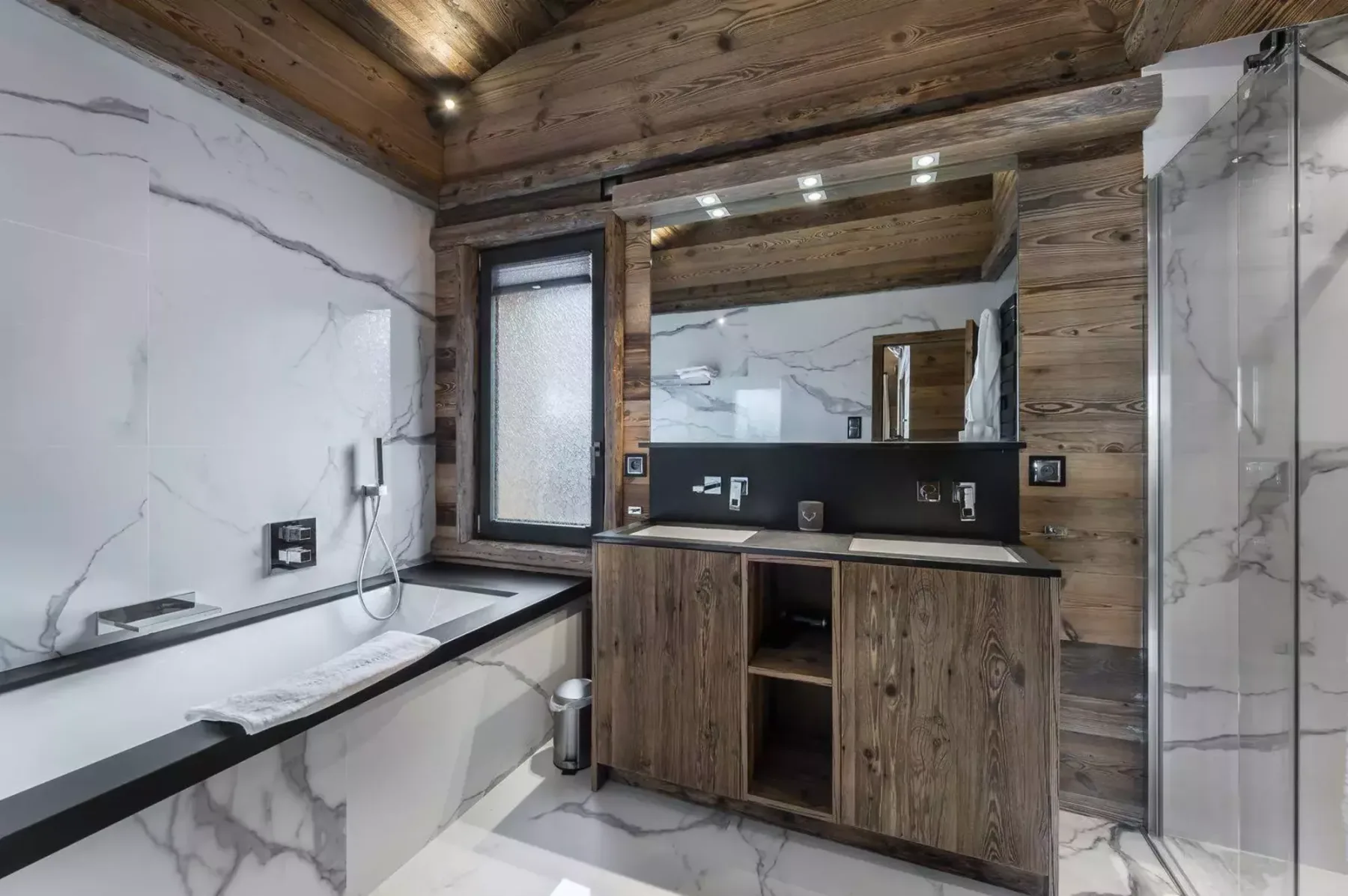 A bathroom with a bathtub, vanity, and large mirror.