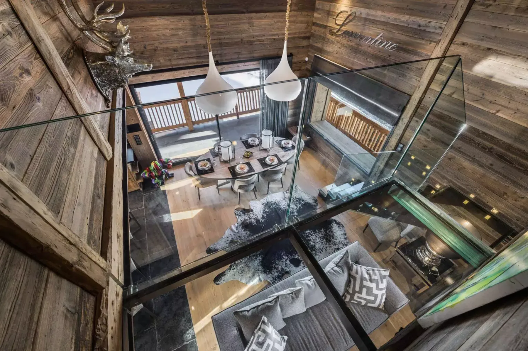 A timber-lined living and dining area with a table, seating, and pendant lights.