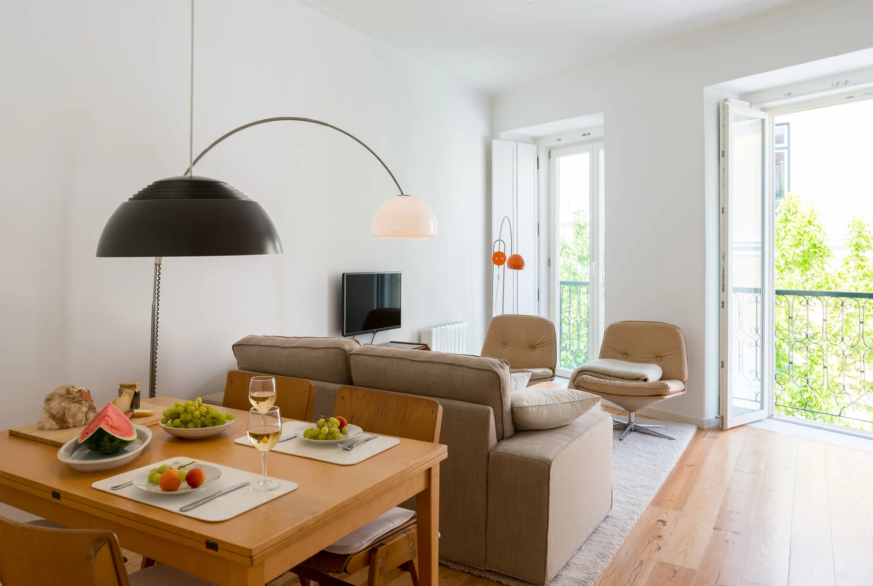 Una luminosa sala de estar y comedor con asientos y una puerta abierta al balcón.