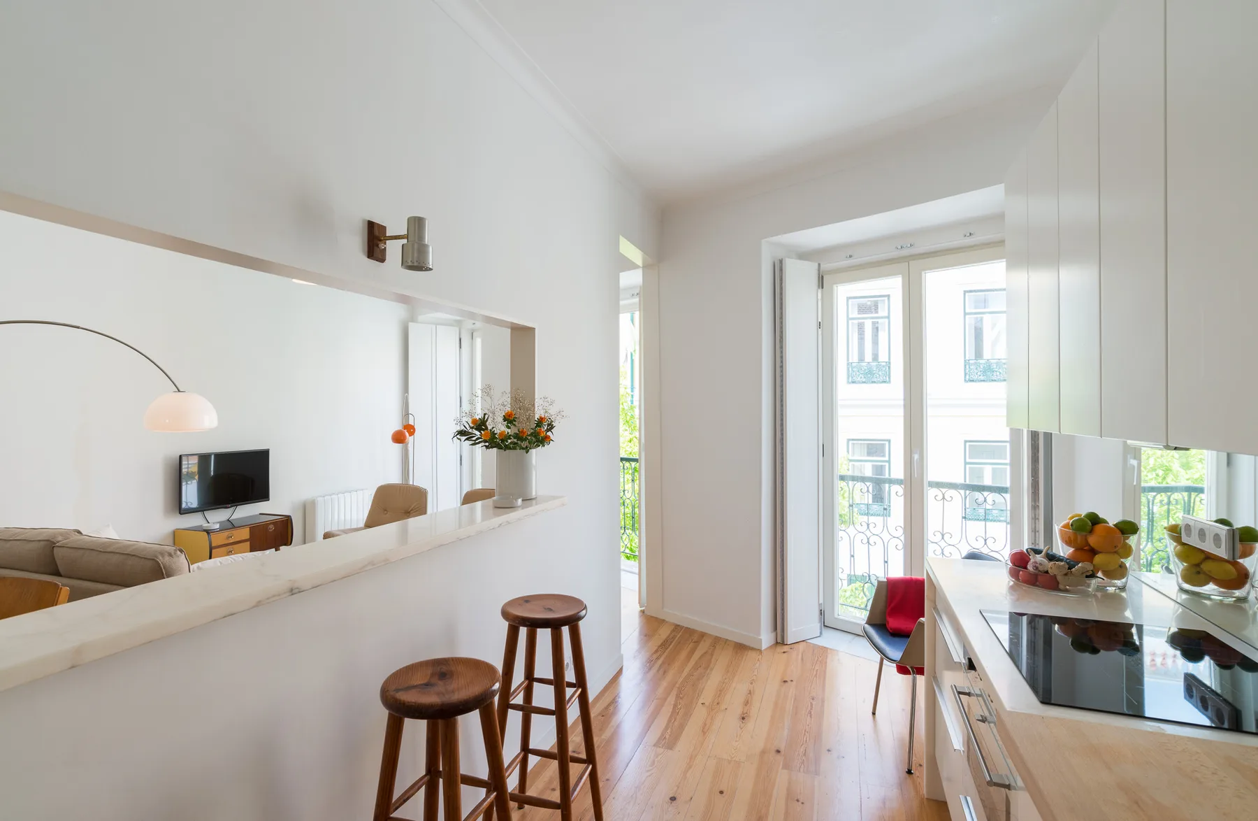 Una luminosa sala de estar y cocina de concepto abierto, con una barra y taburetes altos.