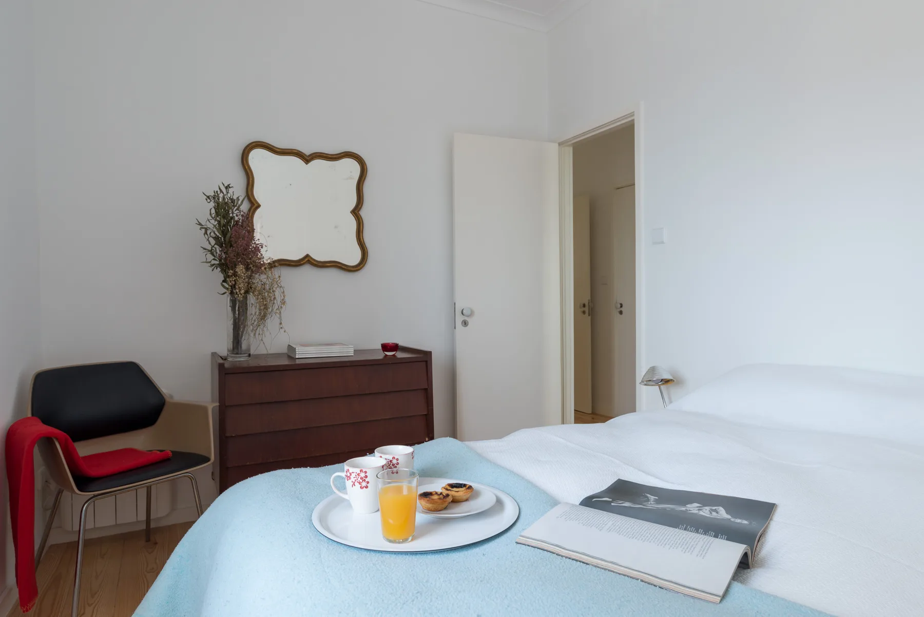 Un dormitorio con una cama, una bandeja de desayuno y una cómoda.