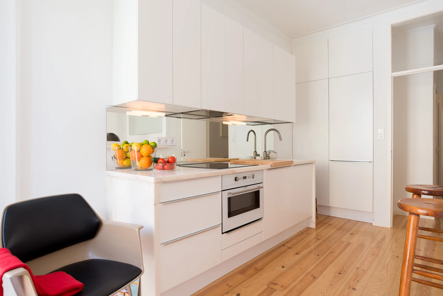 Una cocina blanca y luminosa con encimera, horno y suelo de madera.
