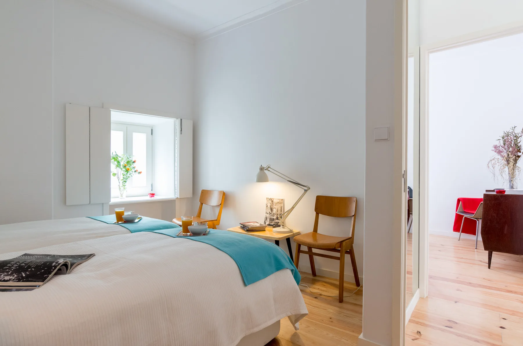 Un dormitorio luminoso con una cama y un pequeño escritorio junto a la ventana.