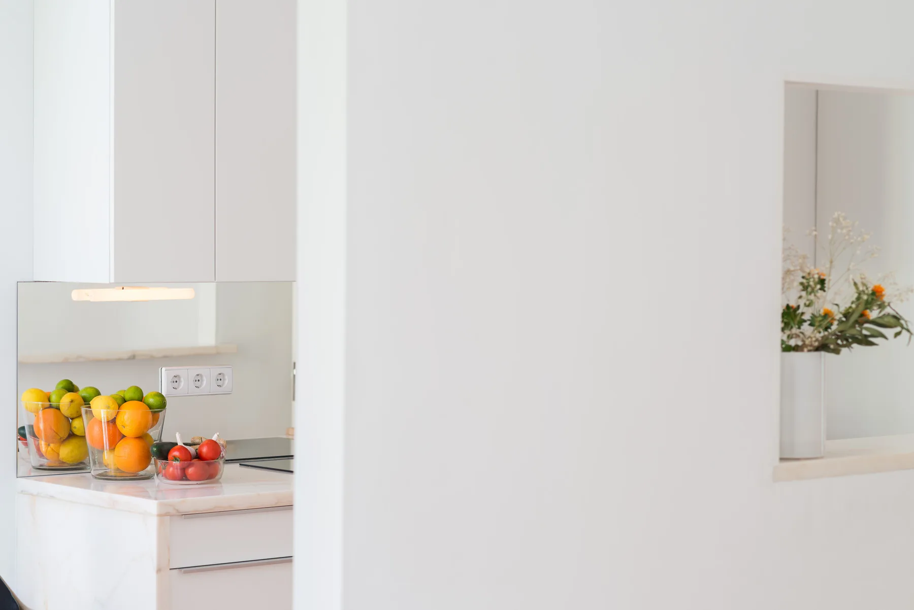Una luminosa encimera de cocina muestra cuencos de fruta junto a una placa de cocción.