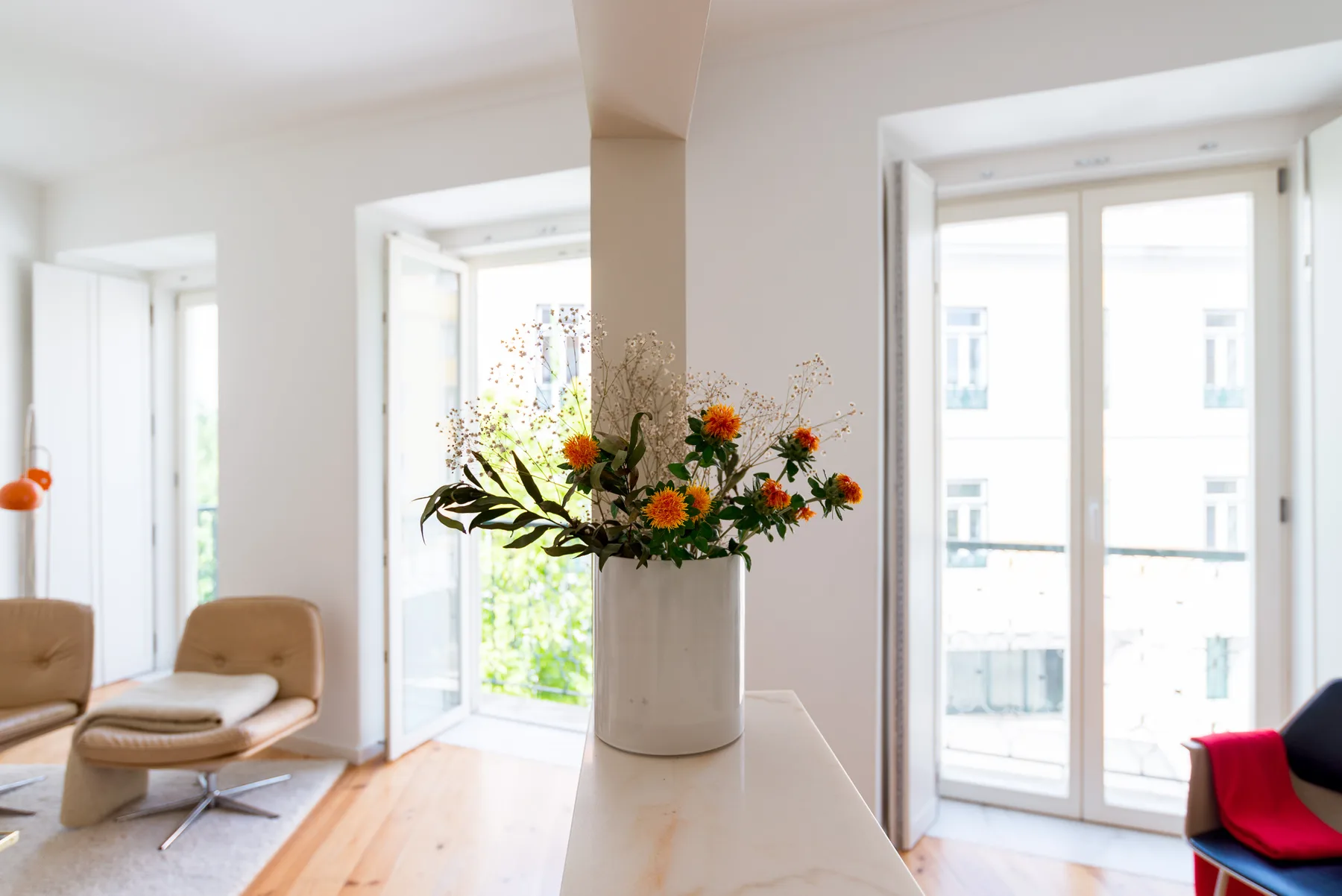 Una sala luminosa con asientos y flores sobre una mesa central.
