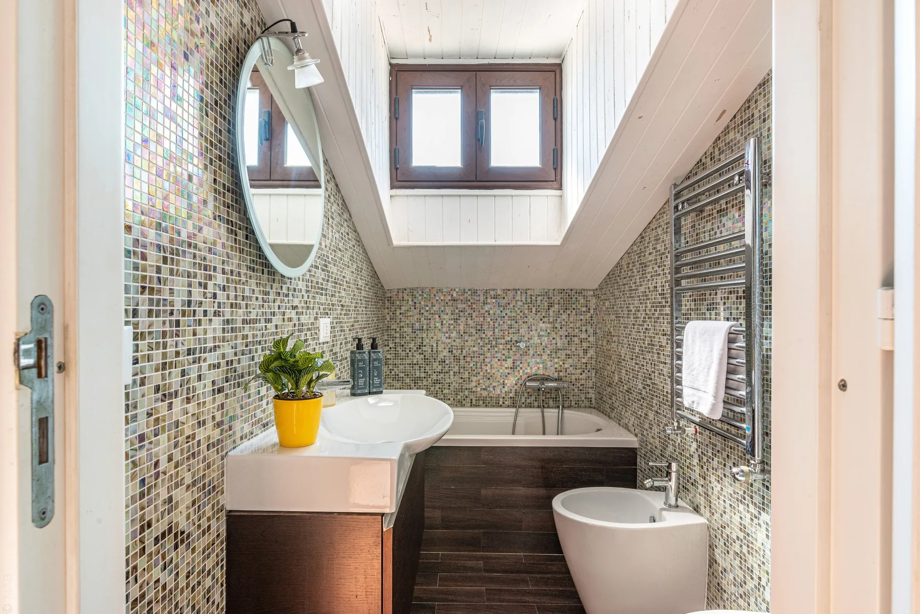 Un baño alicatado con bañera, lavabo y tragaluz.