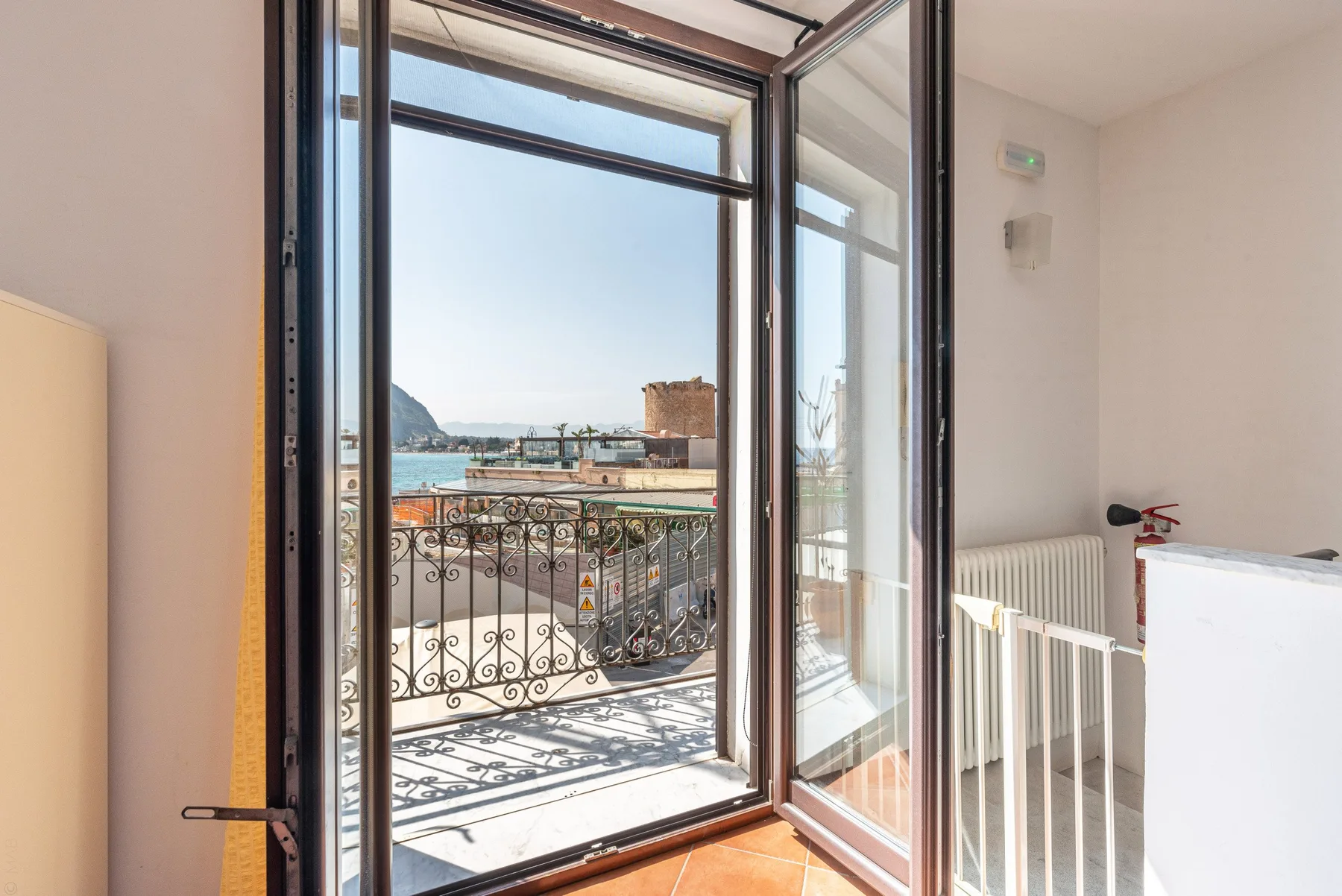 Una habitación luminosa da a un balcón con vistas al paseo marítimo.