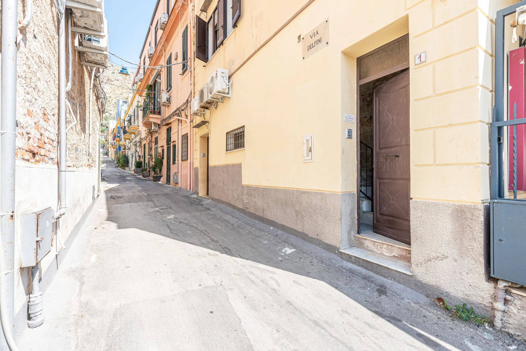 Una calle estrecha pasa entre edificios cercanos, con una puerta abierta.