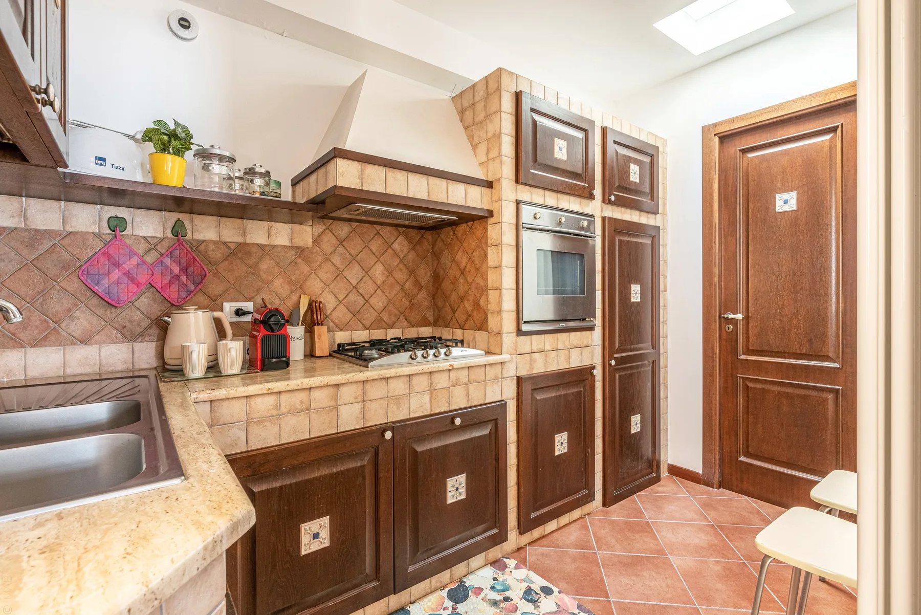 Una cocina con azulejos, gabinetes oscuros, una estufa y electrodomésticos empotrados.