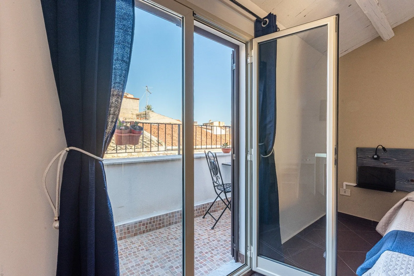 A bedroom opens onto a small tiled balcony with a table and chairs.