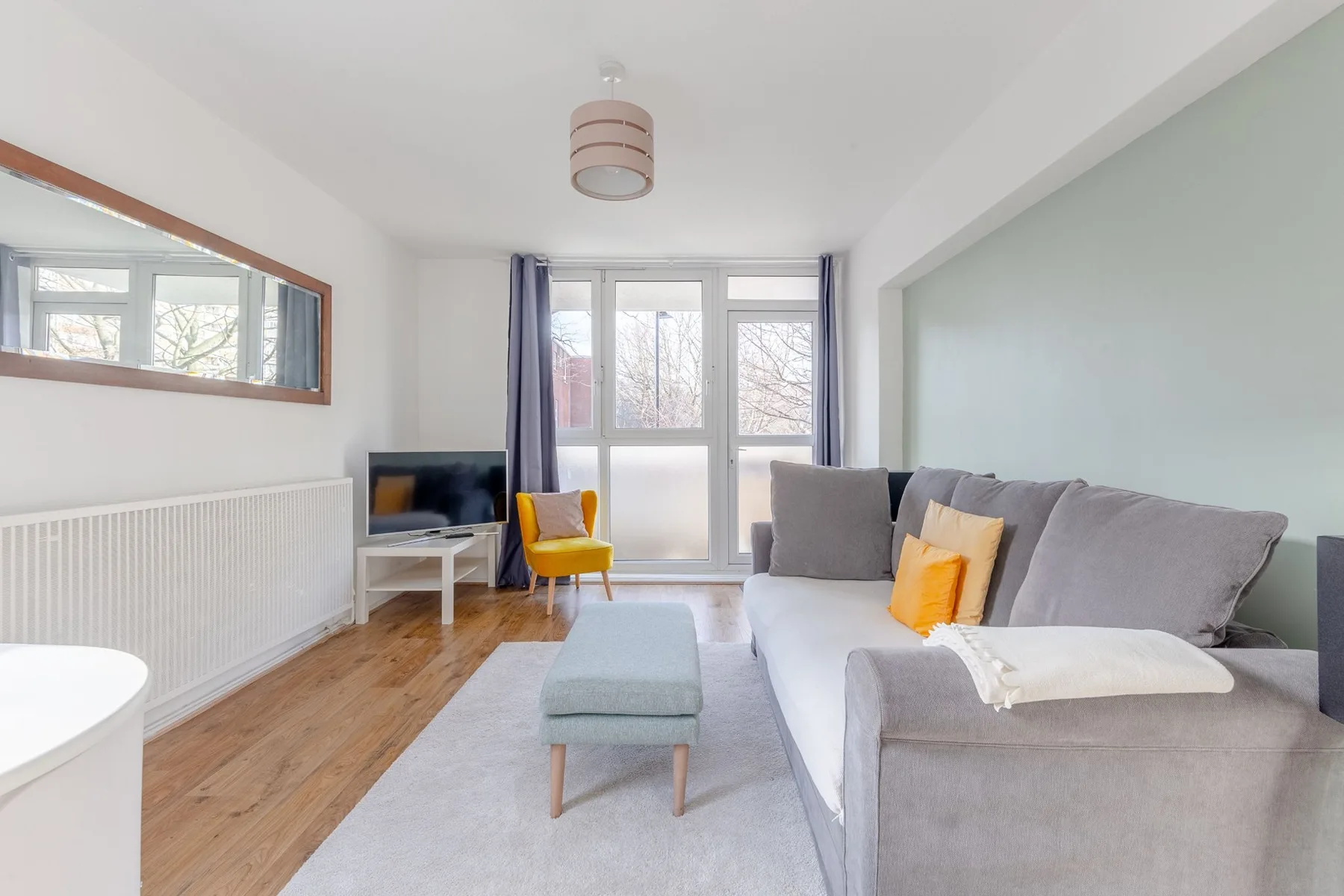 Living room with gray seating, a television, and windows.