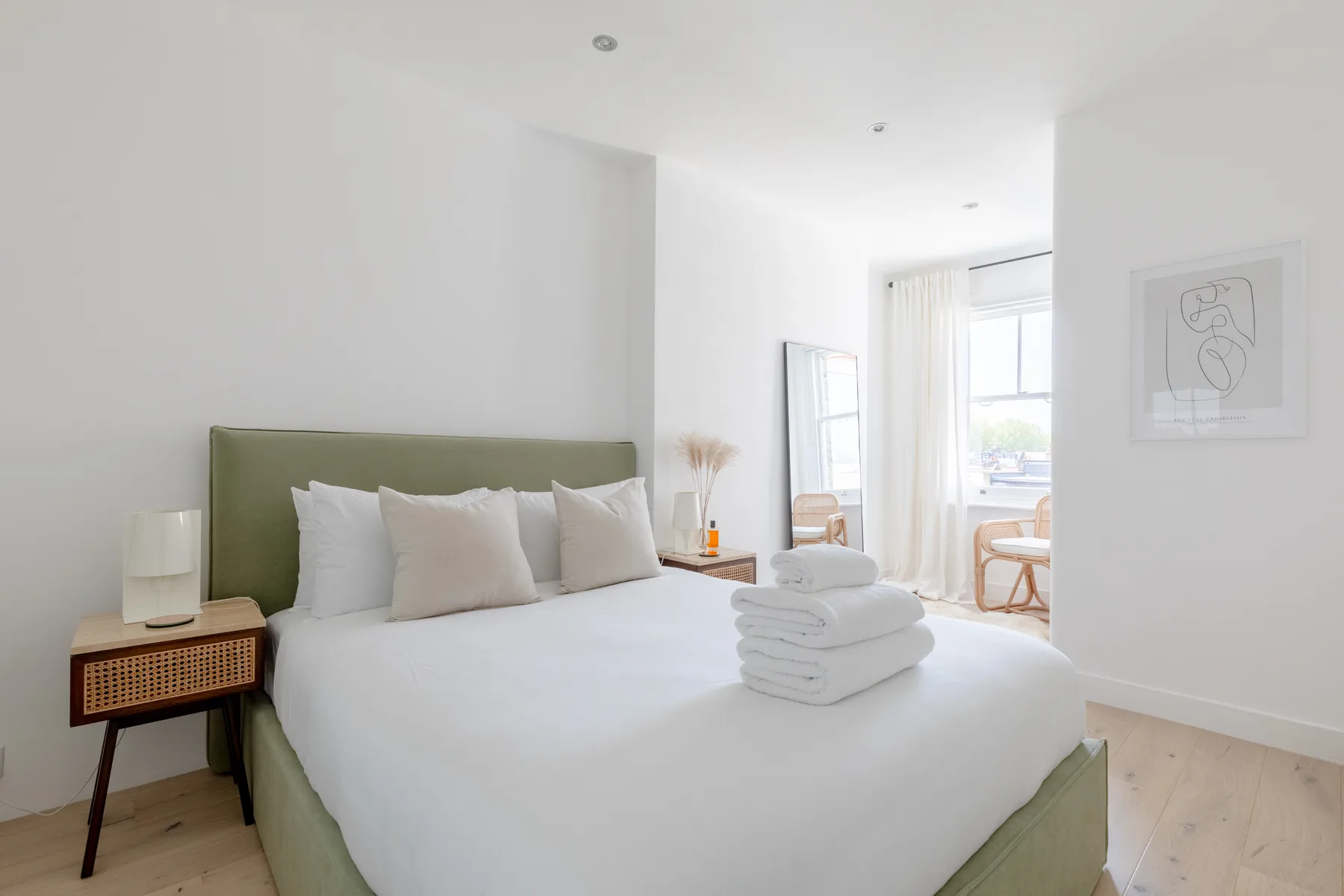 Un dormitorio luminoso con una cama bien tendida y toallas dobladas.