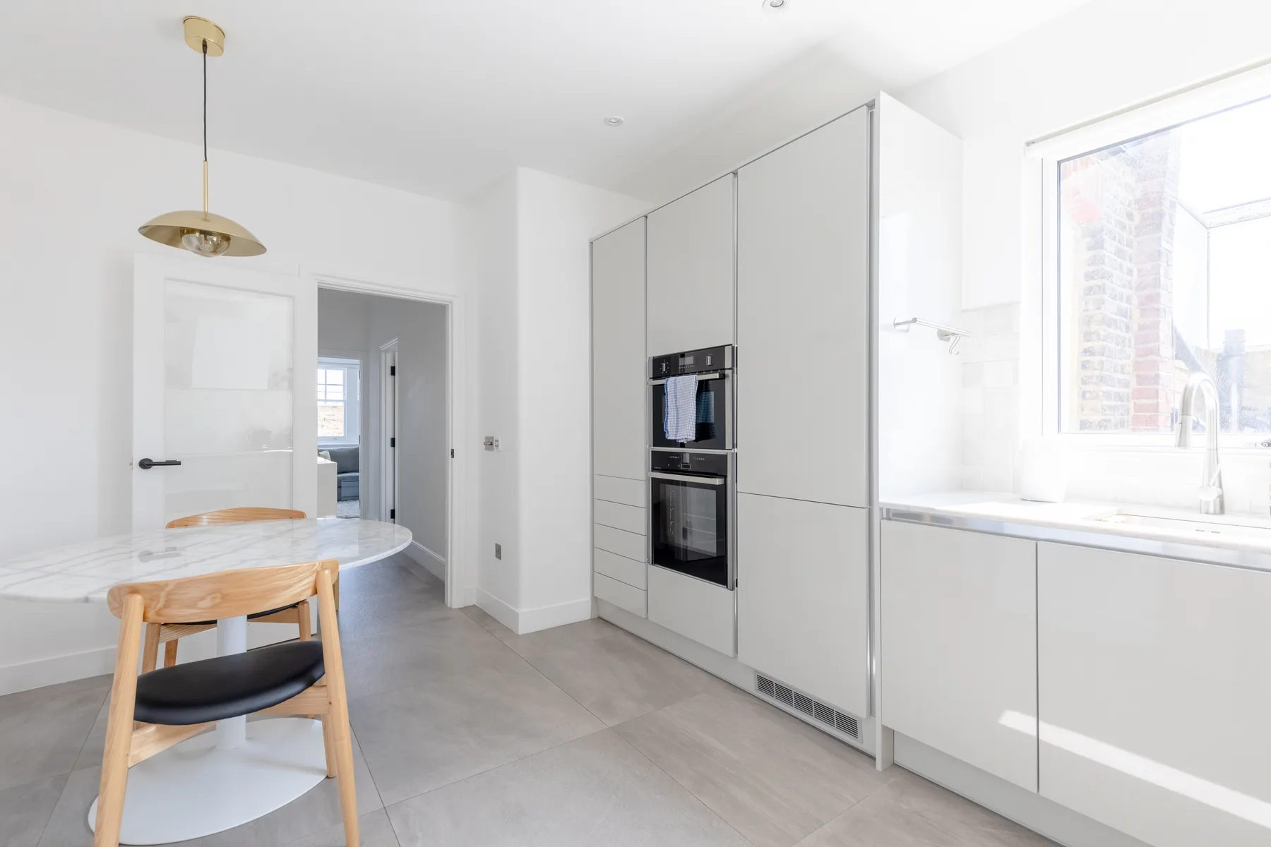 Cocina y comedor luminosos con electrodomésticos integrados y una mesa redonda.