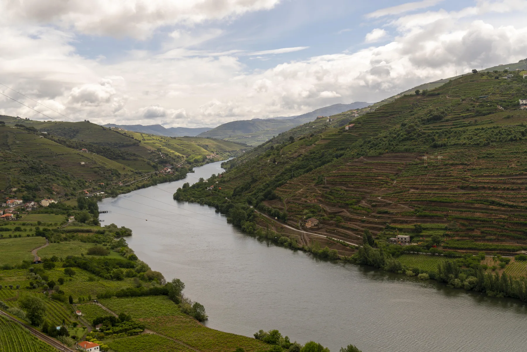Un río serpentea entre colinas verdes y escalonadas bajo un cielo nublado.