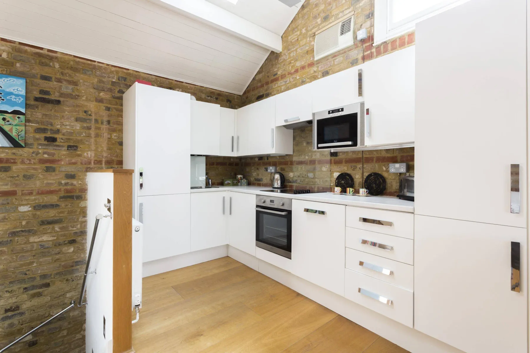 A bright kitchen with white cabinets, built-in appliances, and exposed brick walls.