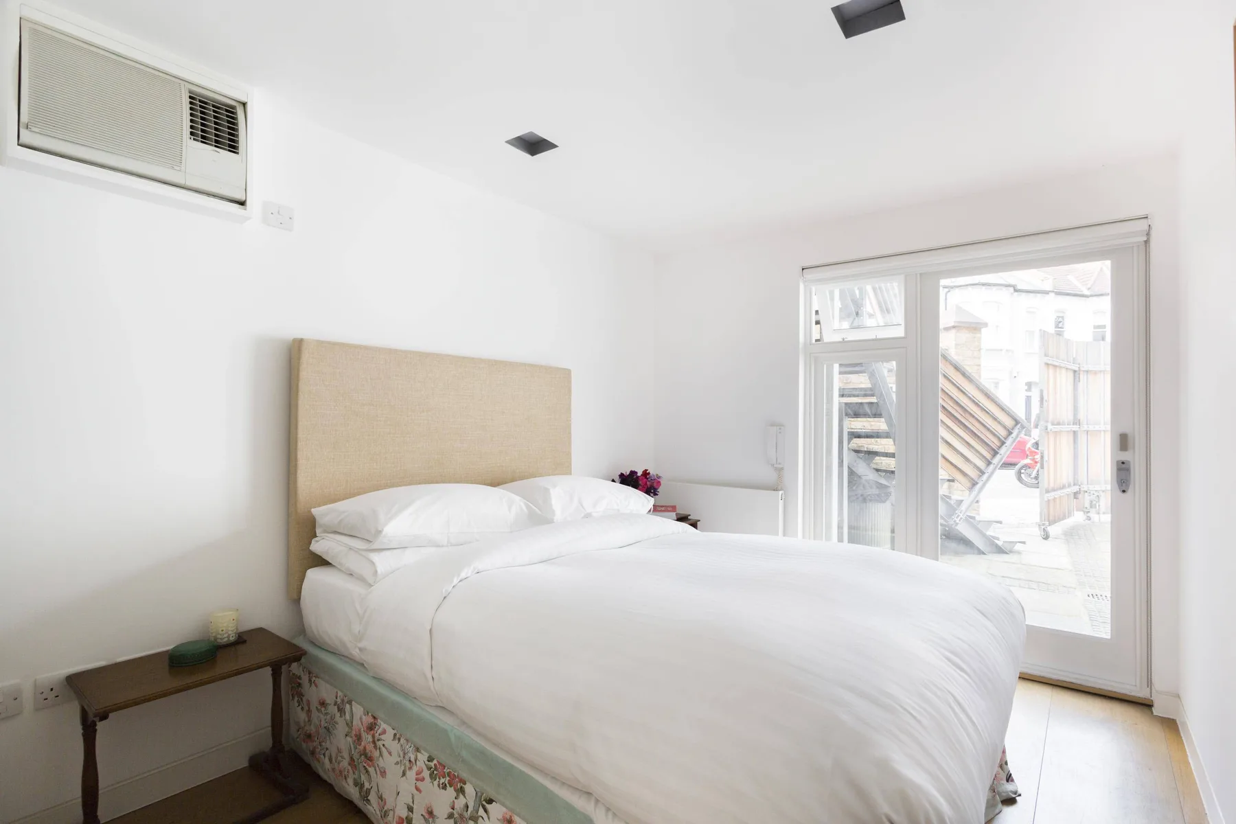 Un dormitorio luminoso con una cama bien hecha y grandes puertas de vidrio.