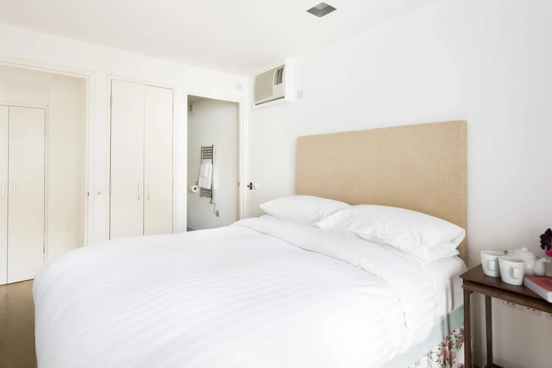 A bright bedroom with a large bed and a bedside table.