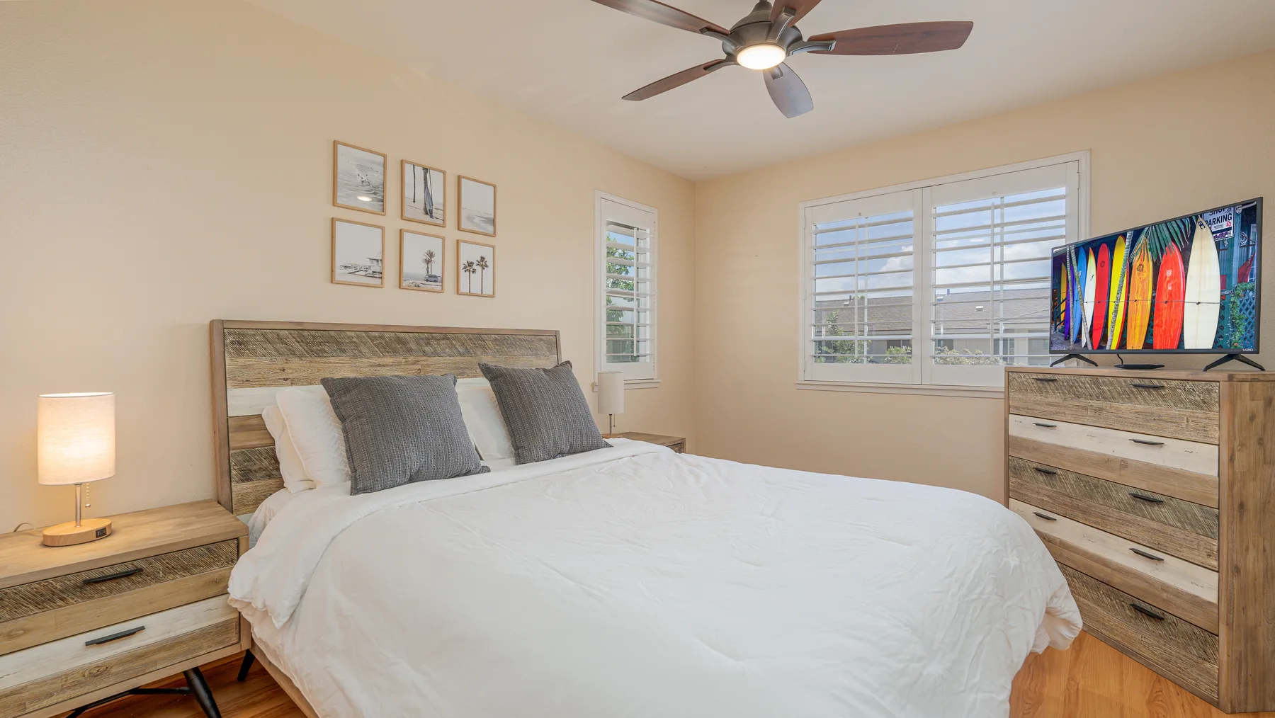 A bedroom with a neatly made bed, bedside tables, and windows.