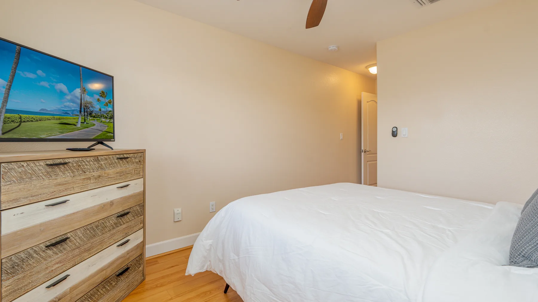 A bedroom with a bed, wooden dresser, and television.