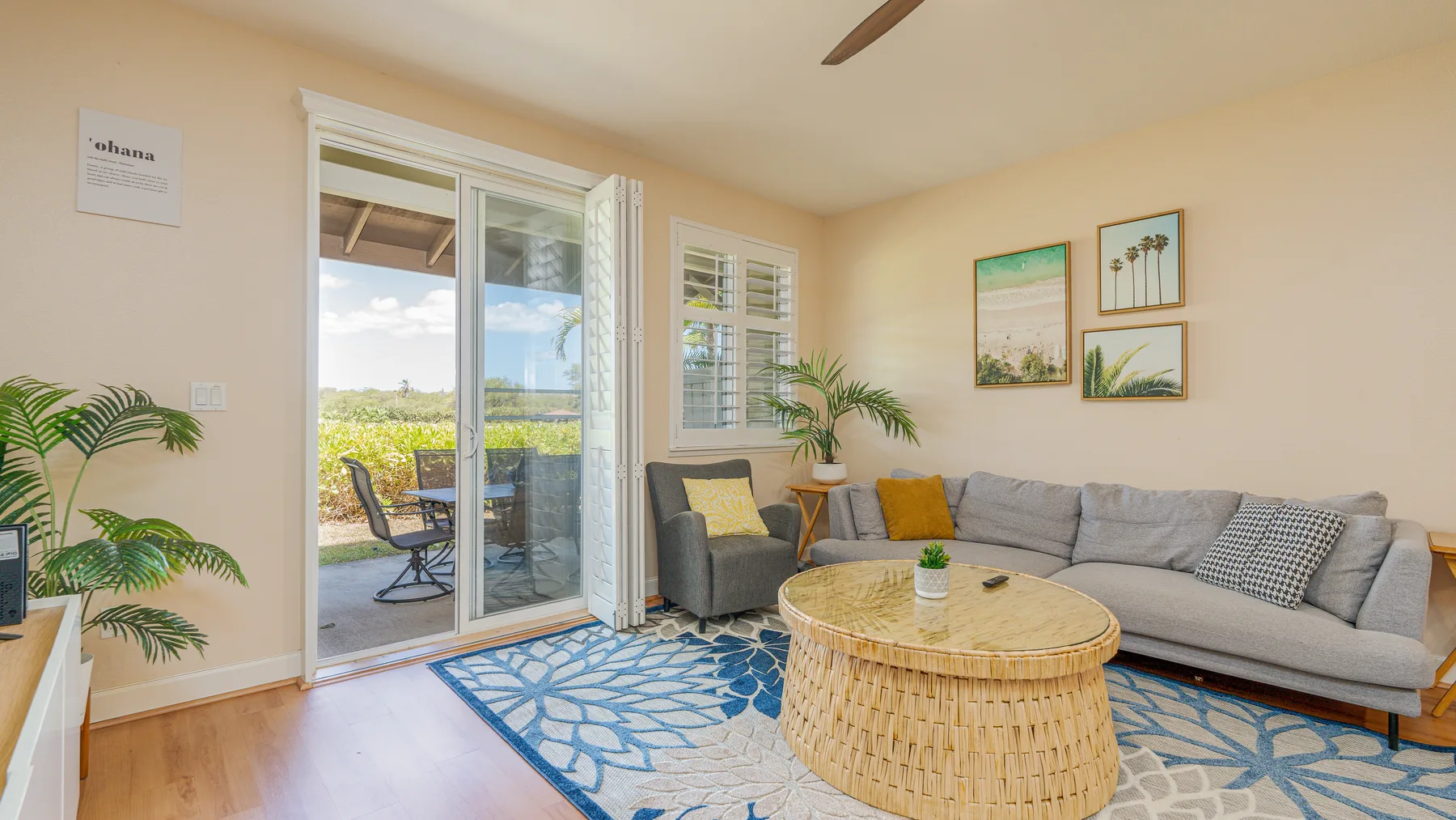 A bright living room with a gray sectional and a round woven coffee table.