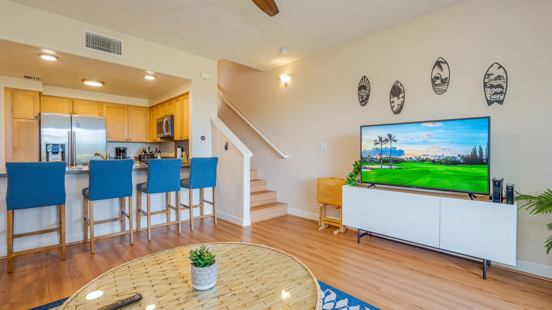 An open-plan living area with a television, dining counter, and kitchen.