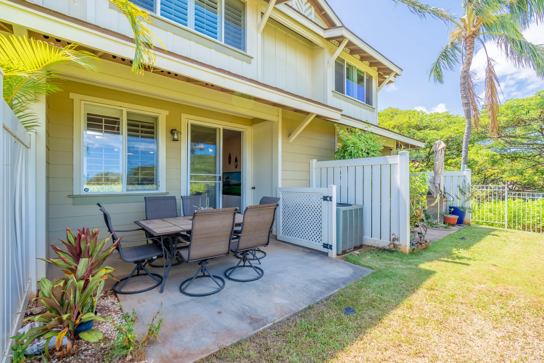 A townhouse patio with an outdoor dining table and seating beside the lawn.