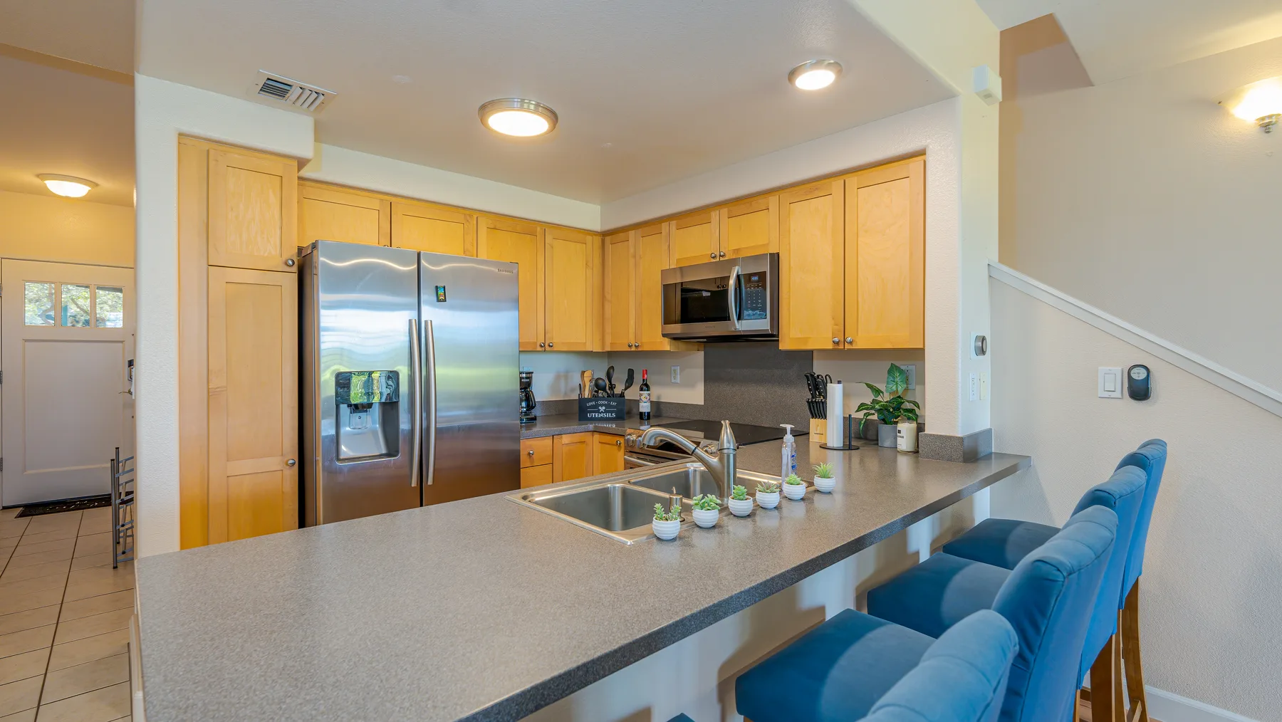 A kitchen with wooden cabinets, stainless steel appliances, and a counter with seating.