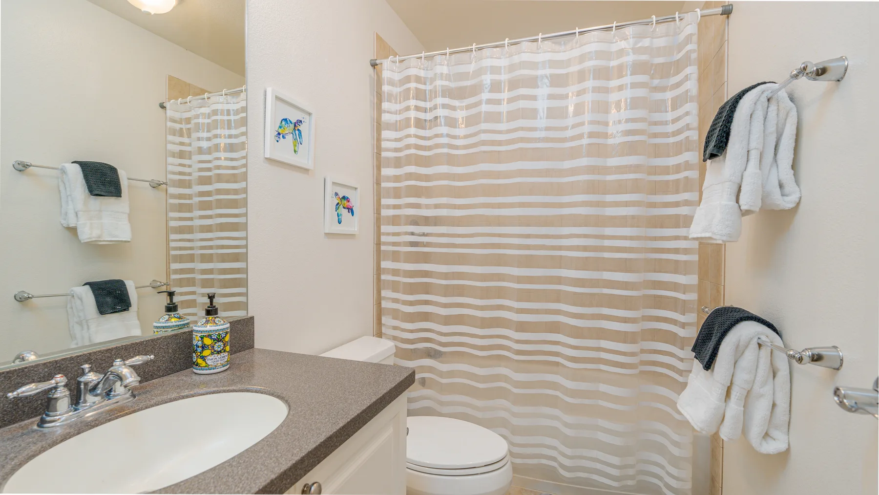 A bathroom vanity and sink face a striped shower curtain.