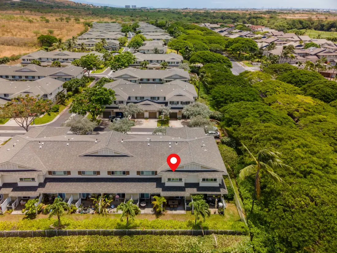 An aerial view of a residential complex with rows of low-rise buildings amid greenery.