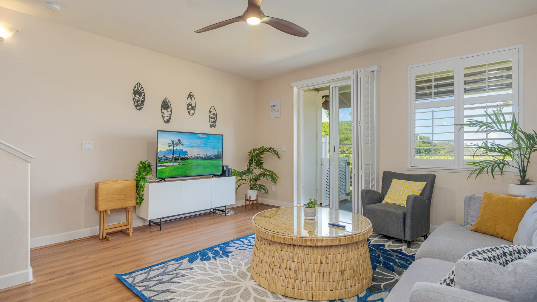 A bright living room with a television, seating, and a round coffee table.