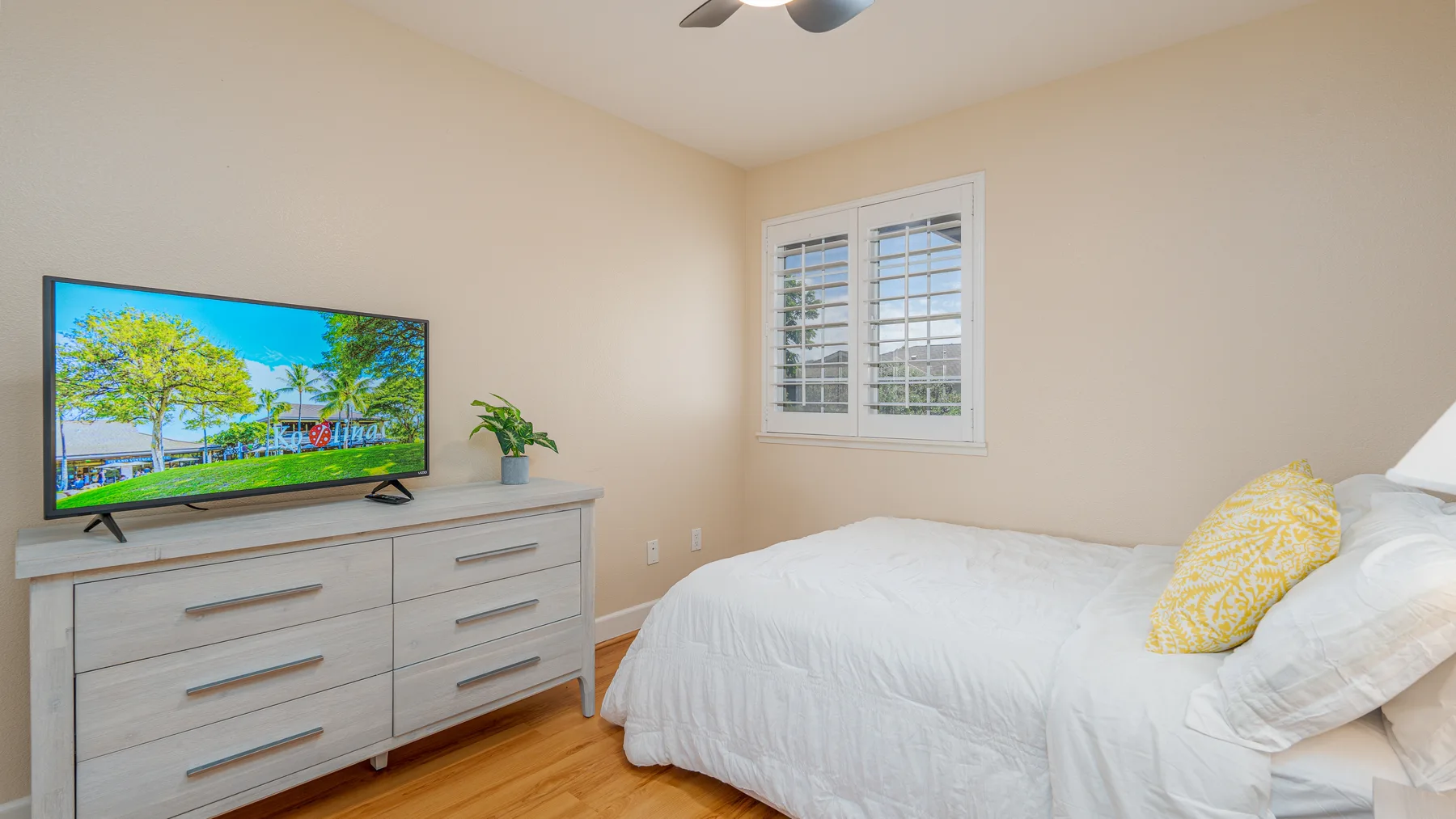 A bedroom with a bed, a dresser, and a window with shutters.
