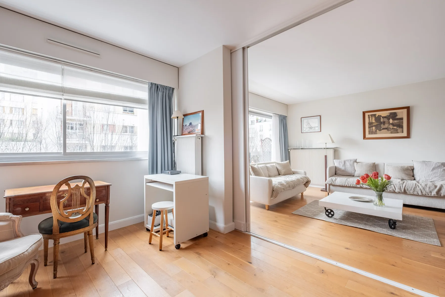 A bright living room with seating around a low table beside large windows.