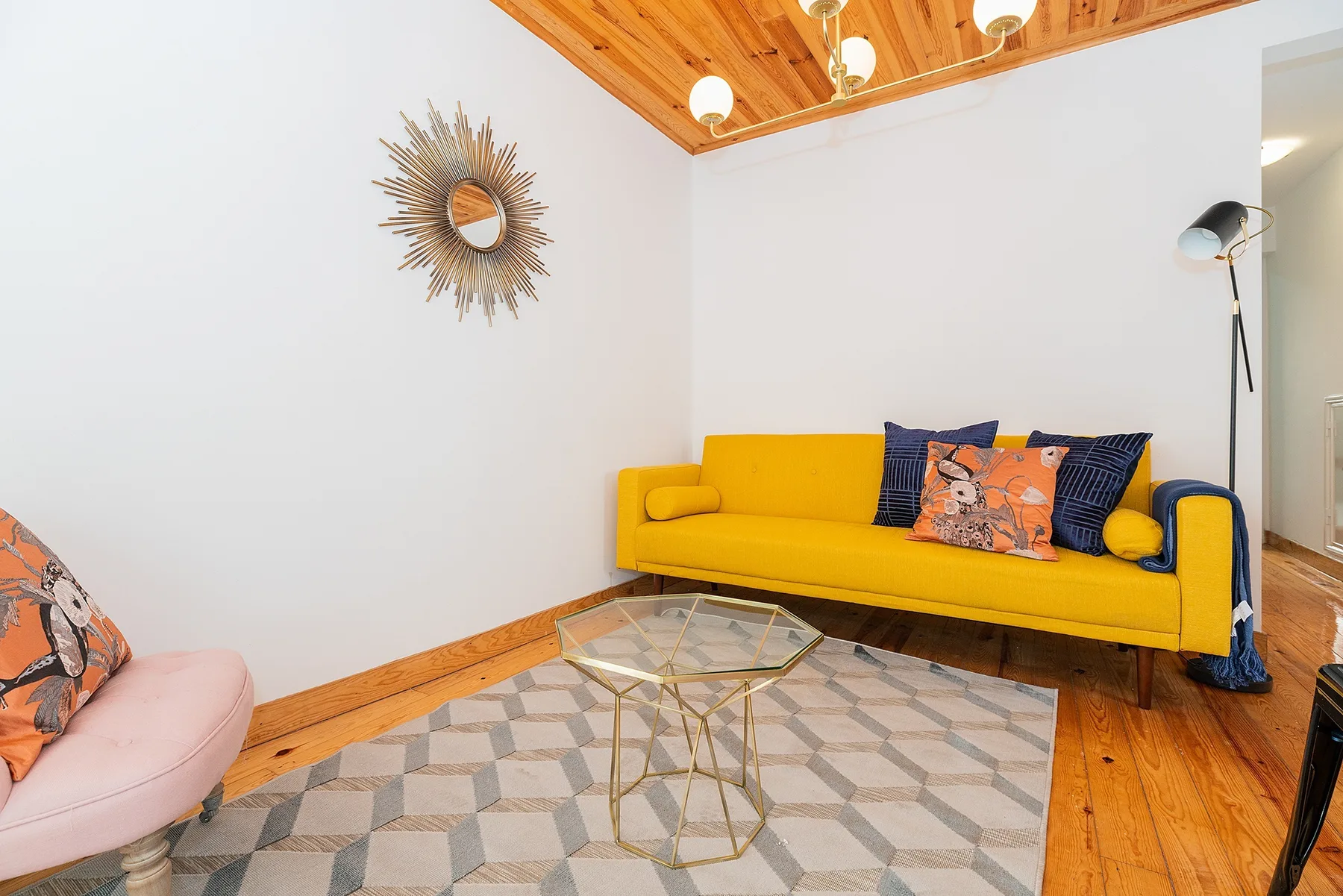 A bright living room with yellow seating and a geometric rug.