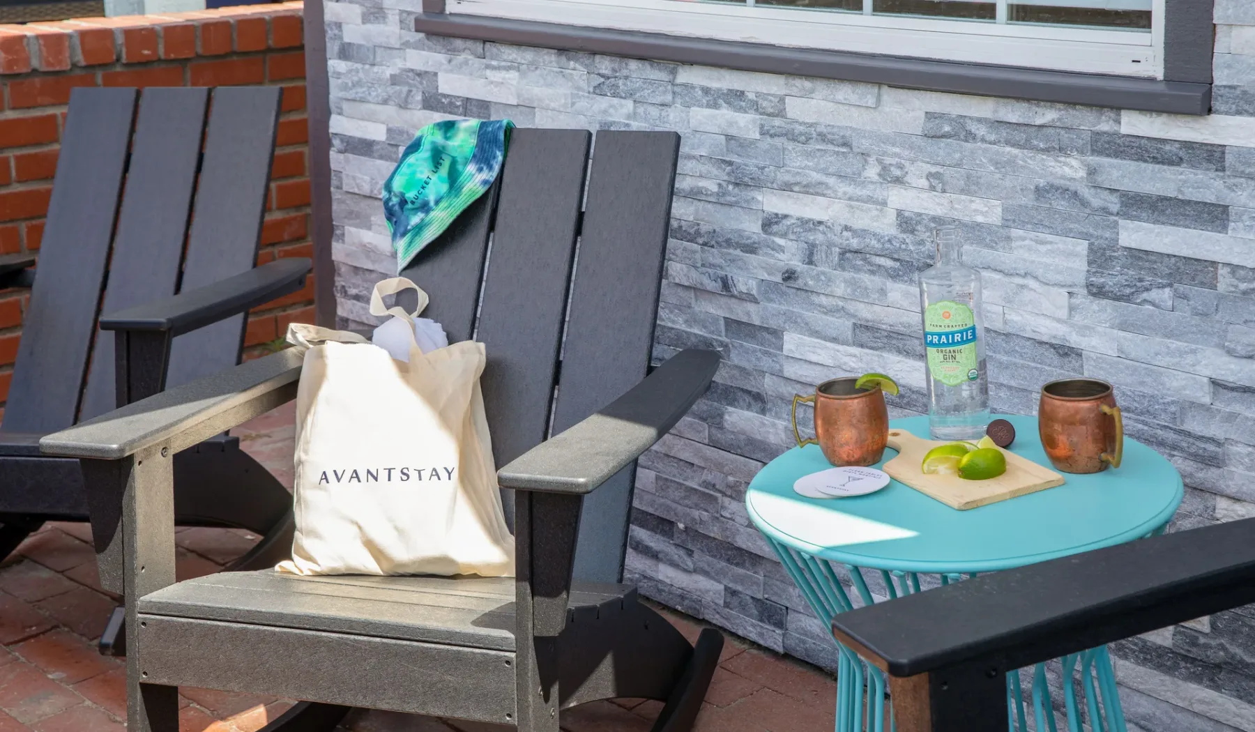 Asientos en un patio junto a una pequeña mesa turquesa con bebidas y fruta.